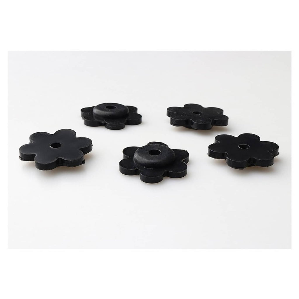 Five black flower-shaped rubber flag stops with center holes, spaced on a flat surface