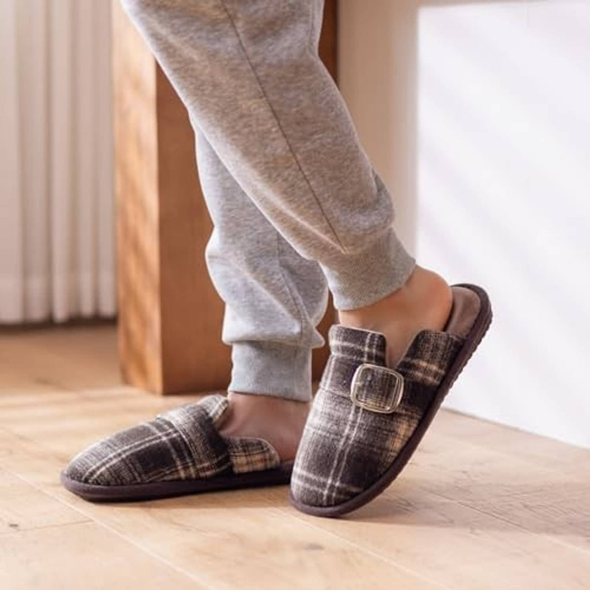 Plaid fuzzy slide slippers with buckle strap and cushioned footbed, worn by person