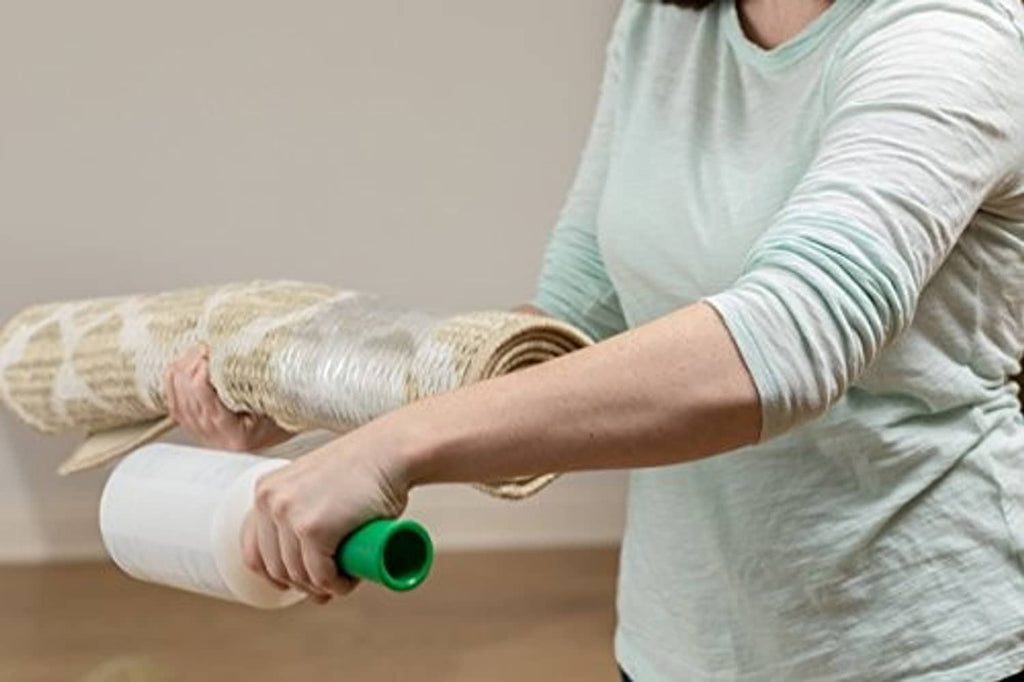 Person applying Duck Brand stretch wrap roll around rolled items with green dispenser
