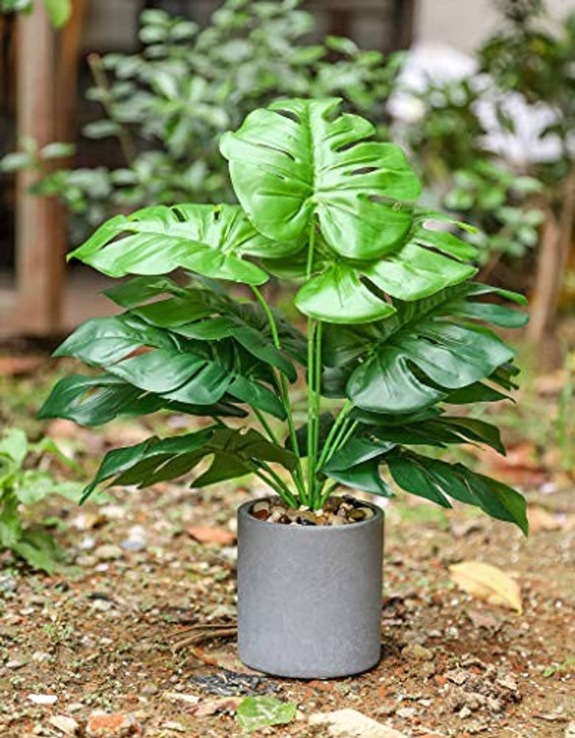 Artificial potted tropical plant with large split-leaf foliage in gray pot