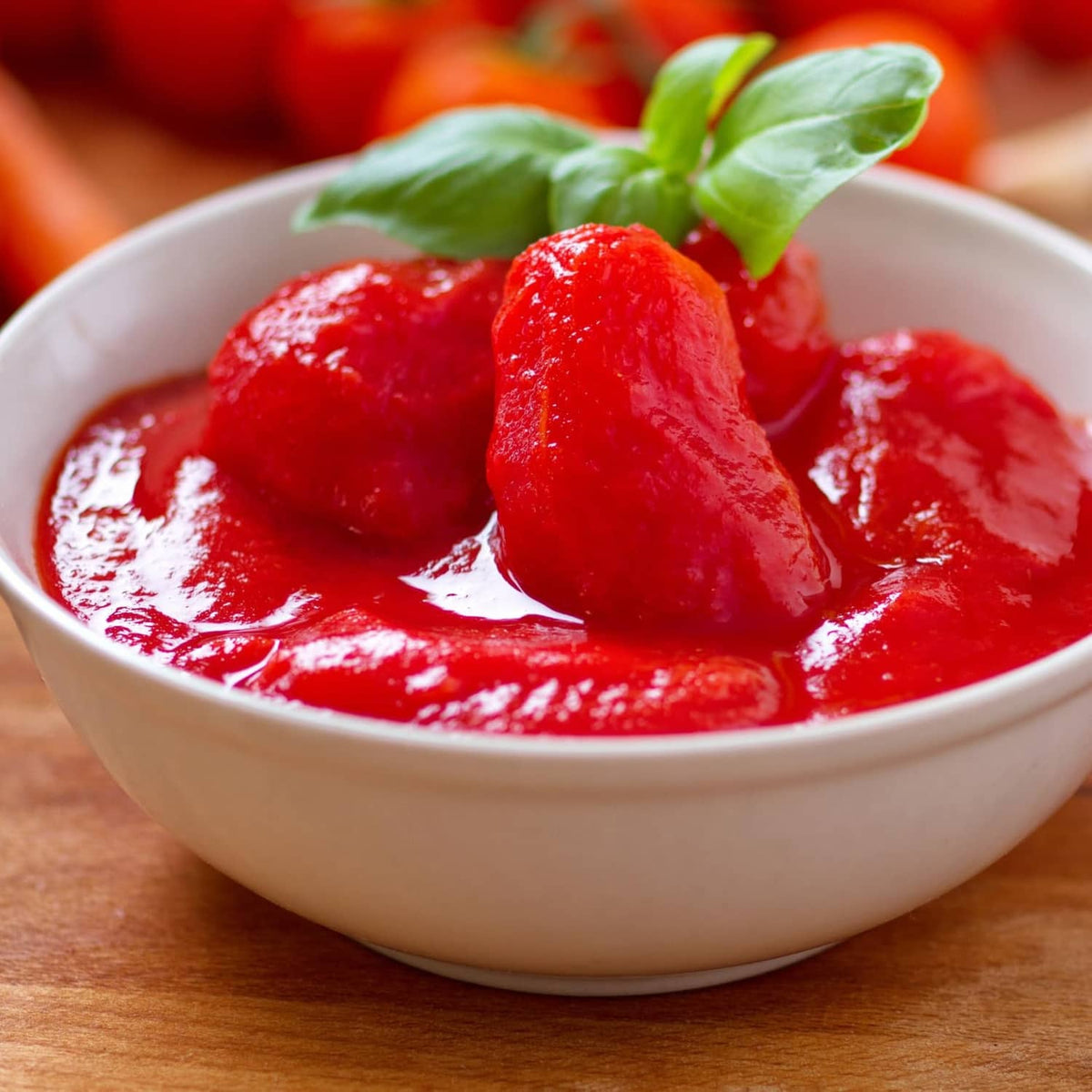 Ground peeled tomato sauce in bowl topped with whole tomatoes and basil