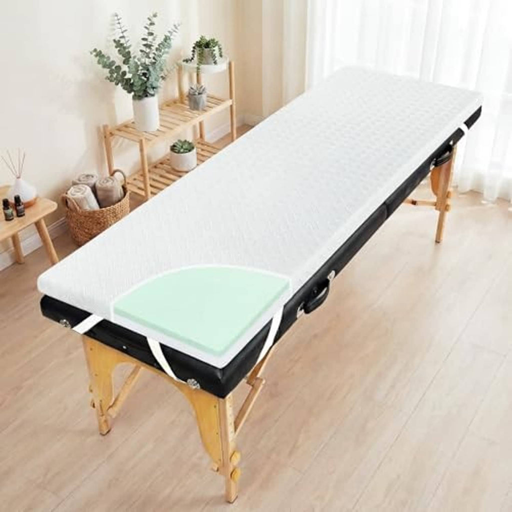 White memory foam massage table topper on black massage bed frame, angled view