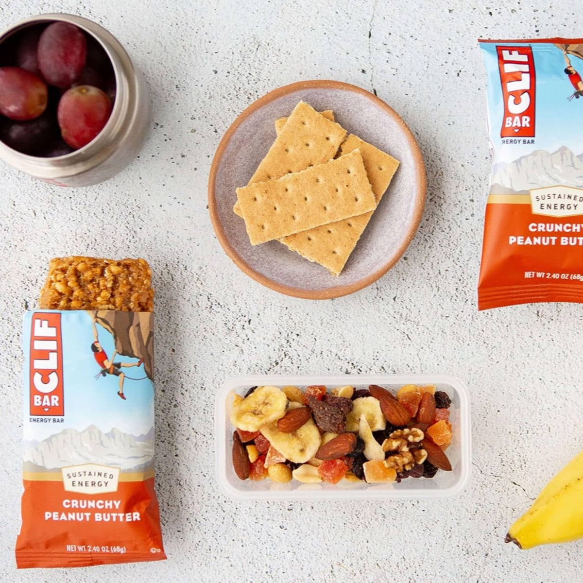 CLIF crunchy peanut butter energy bar with crackers, trail mix bowl, and fruit