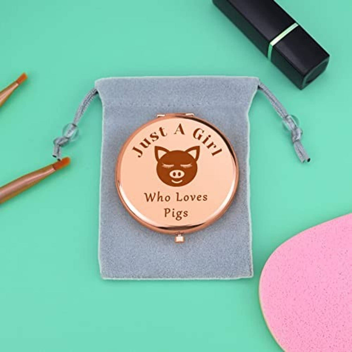 Rose-gold compact makeup mirror in a gray drawstring pouch with pig design