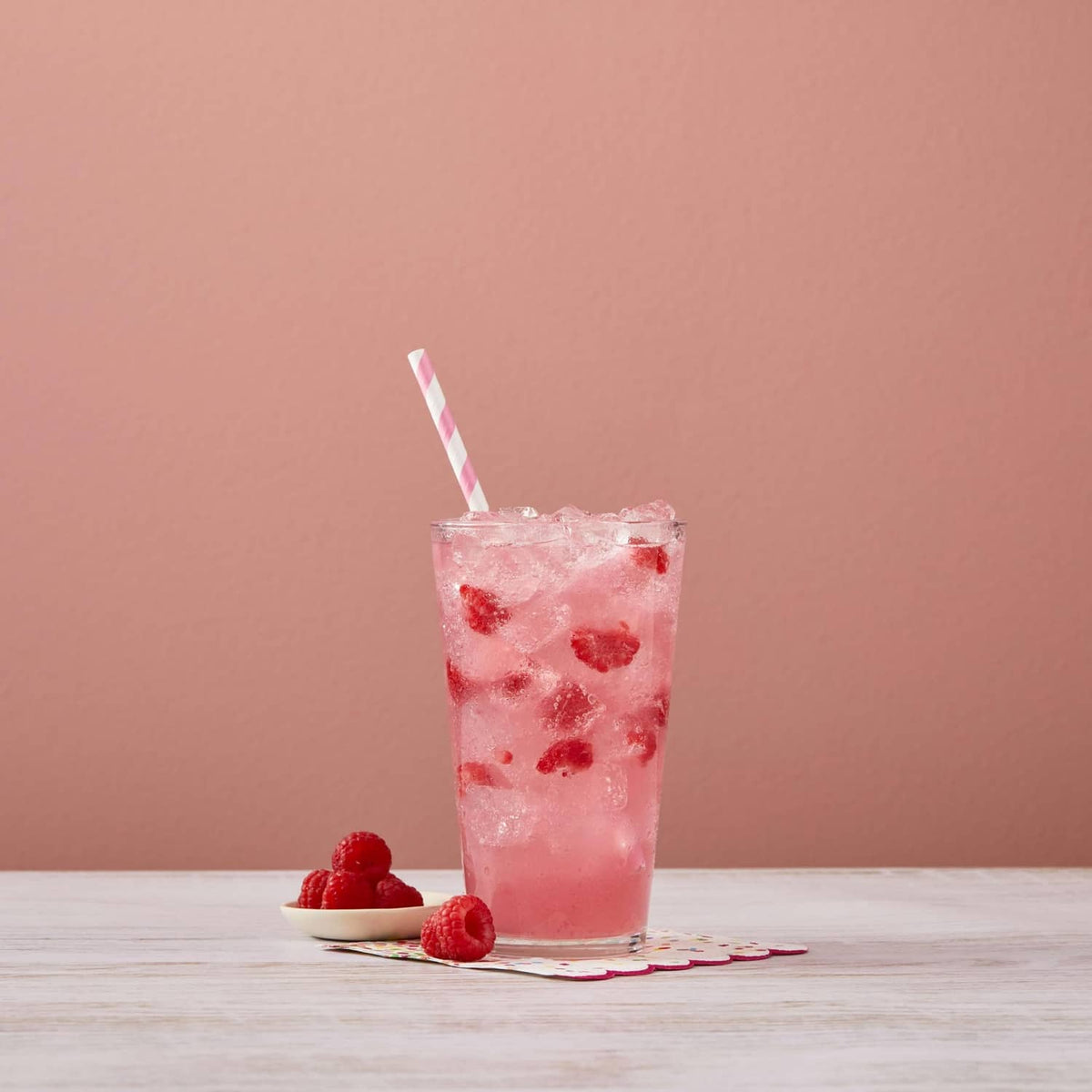 Glass of raspberry syrup drink with crushed ice and raspberries