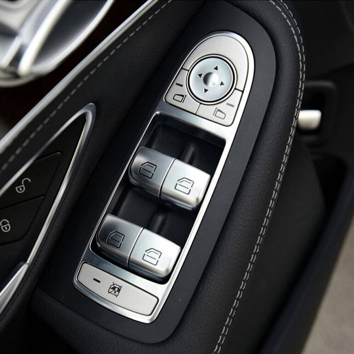 Power window switch panel with silver buttons and rotary control on black trim