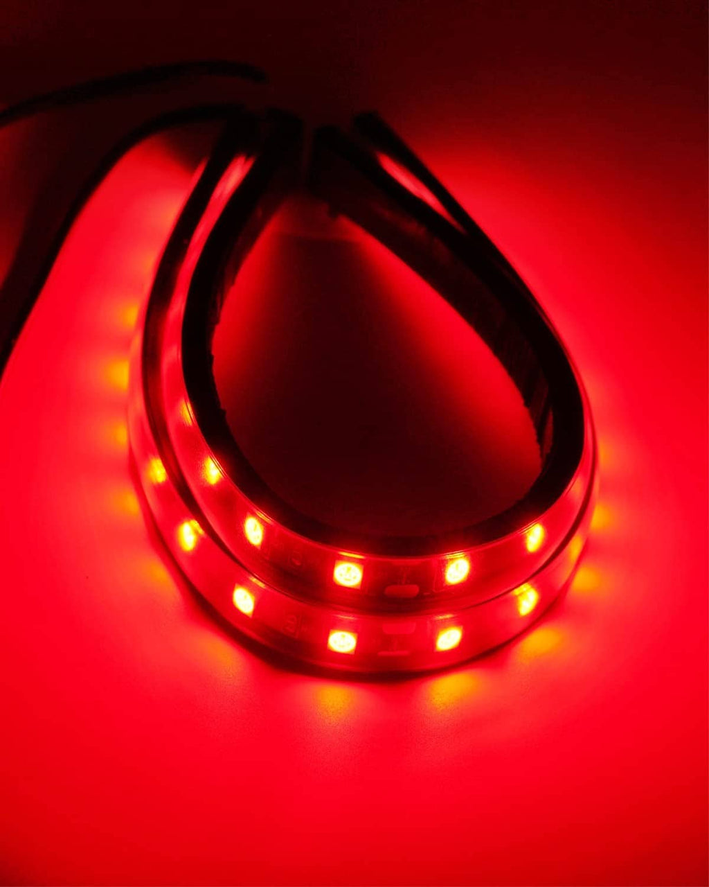 Close-up red LED light strip with curved glowing segments on waterproof tape