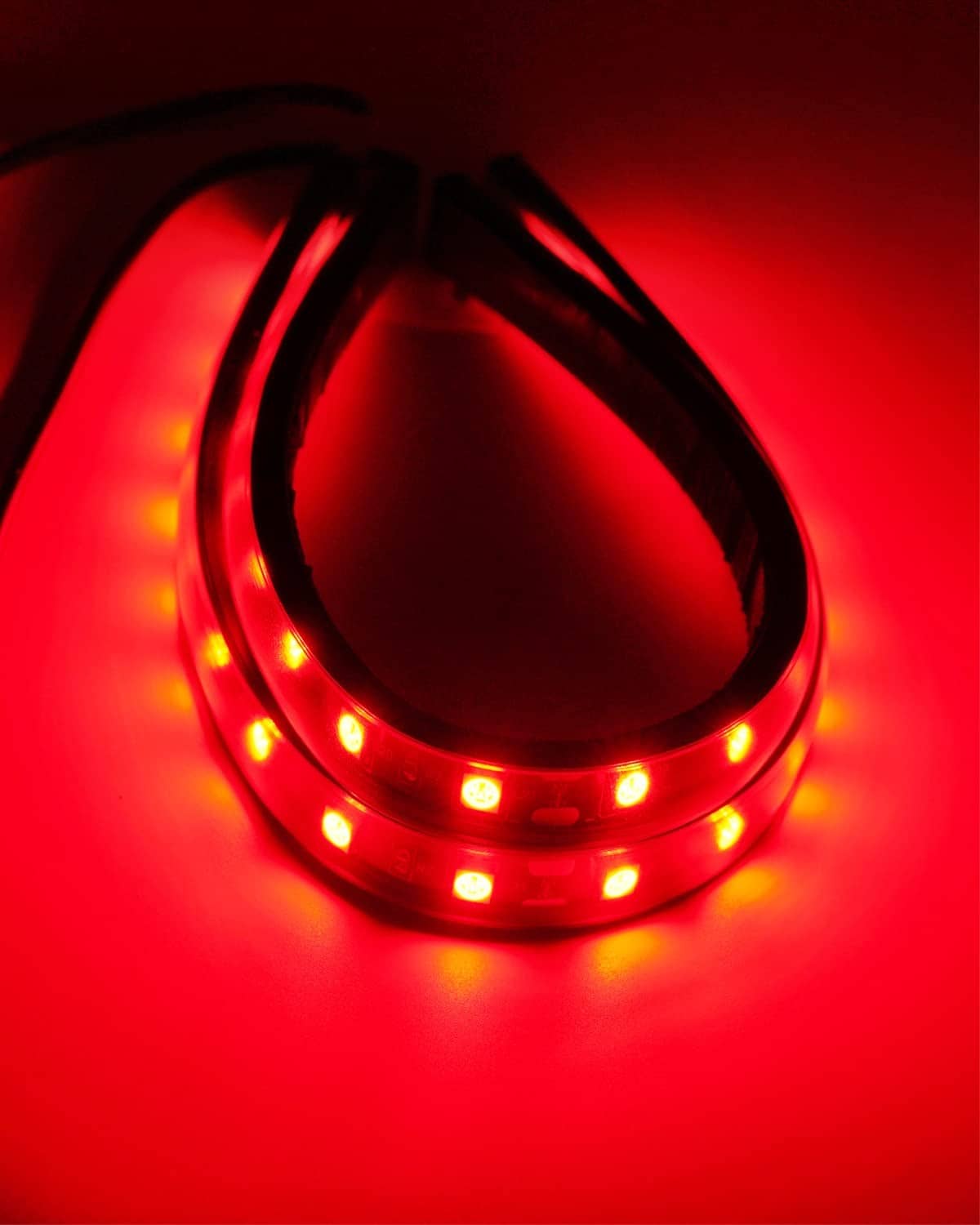 Close-up red LED light strip with curved glowing segments on waterproof tape