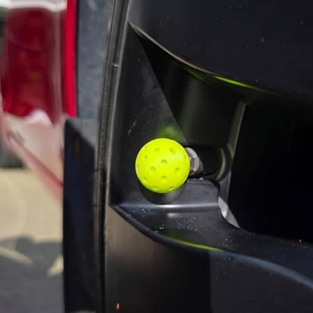 Lime-green ball-textured valve stem cap installed on a car wheel valve.