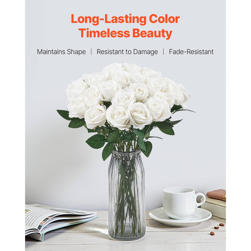 White artificial rose bouquet with green leaves in a clear glass vase