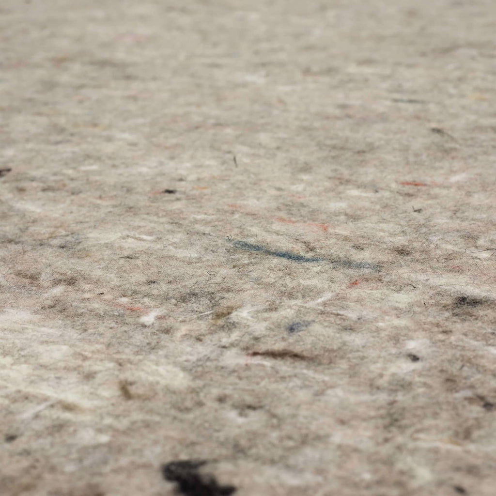 Close-up of speckled light gray felt rug pad texture with fine fibers