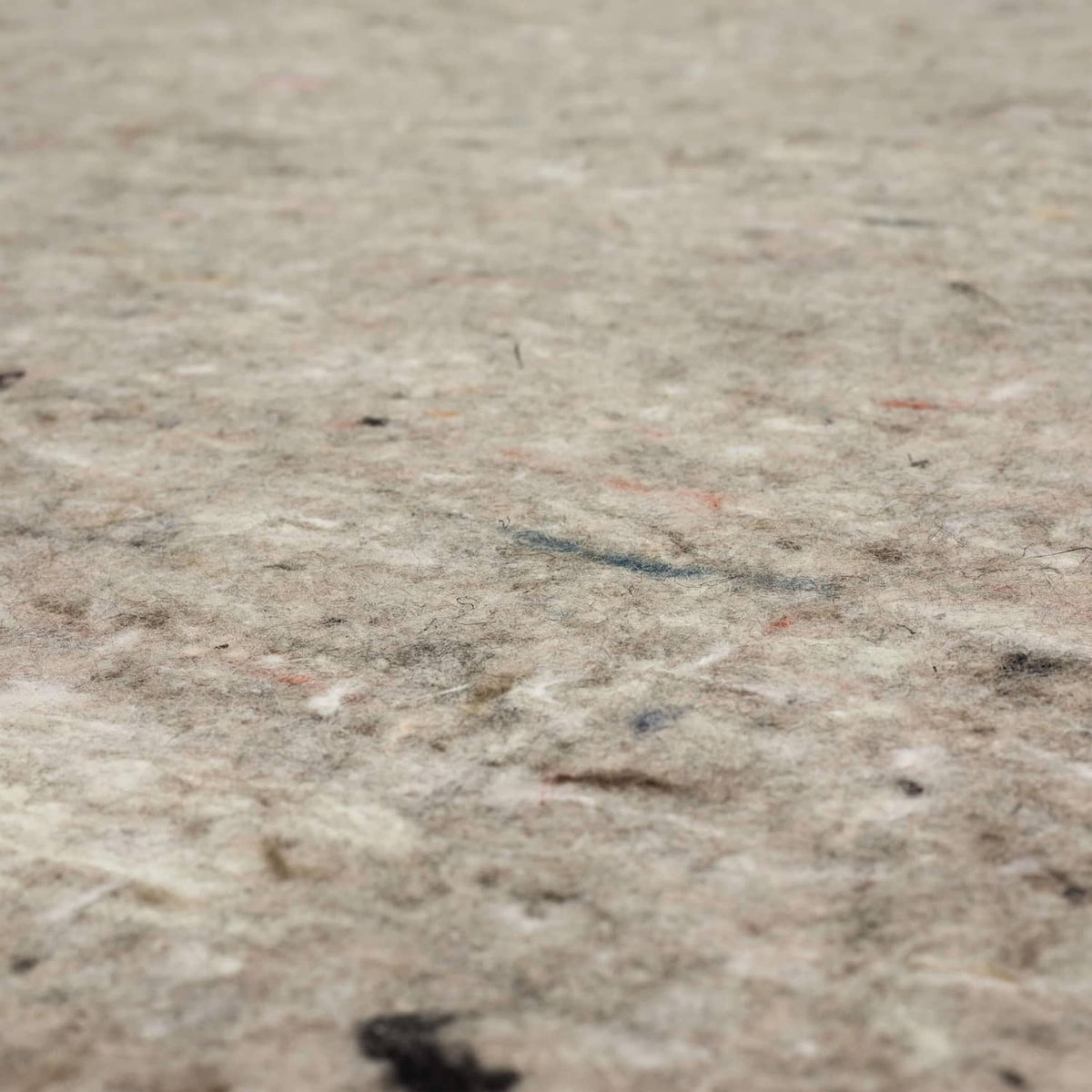 Close-up of speckled light gray felt rug pad texture with fine fibers