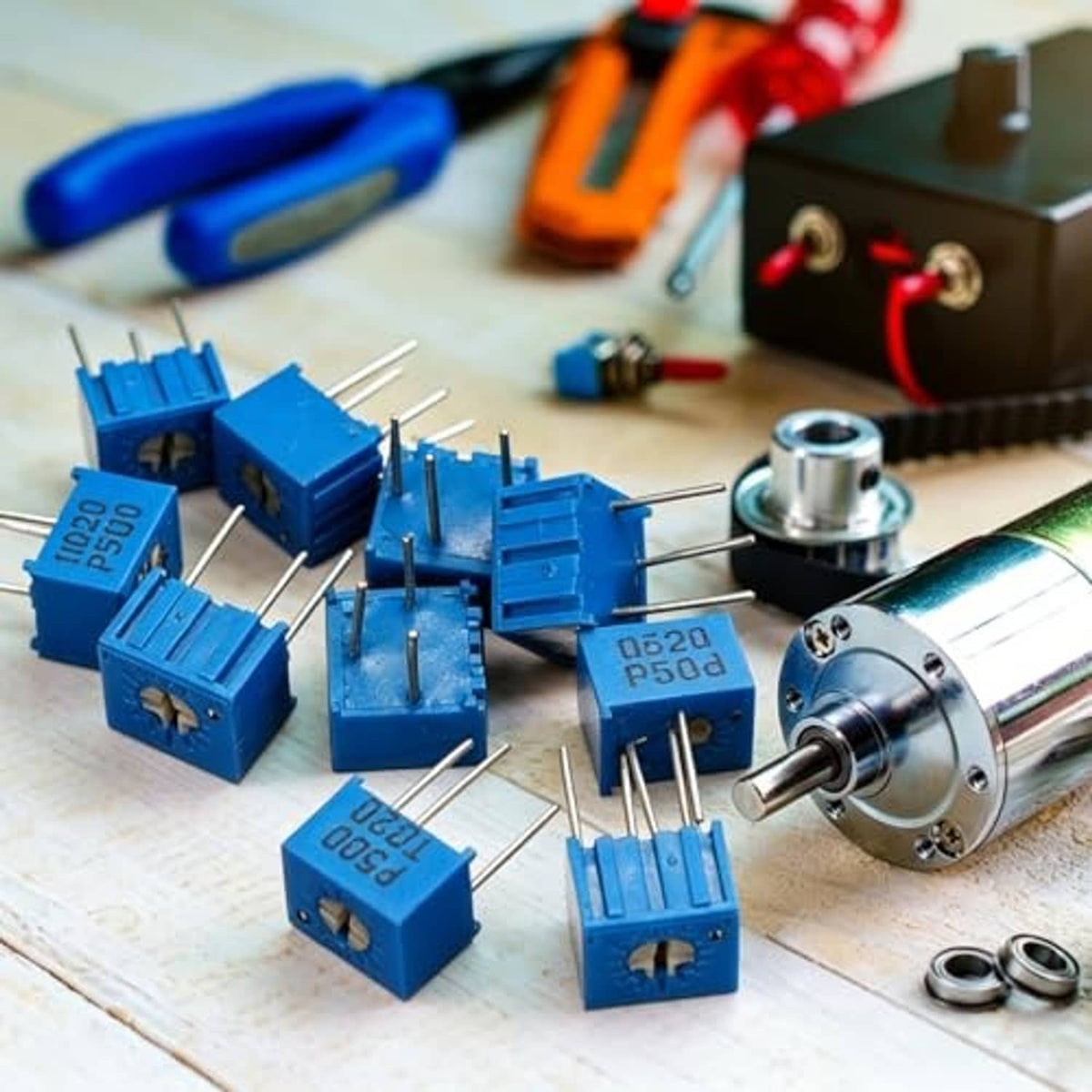 Multiple blue multiturn trimmer potentiometers with metal leads on a workbench