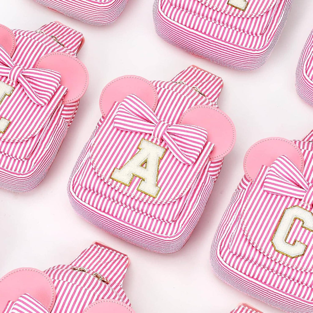 Assorted pink striped sling bags with bow fronts and letter patches