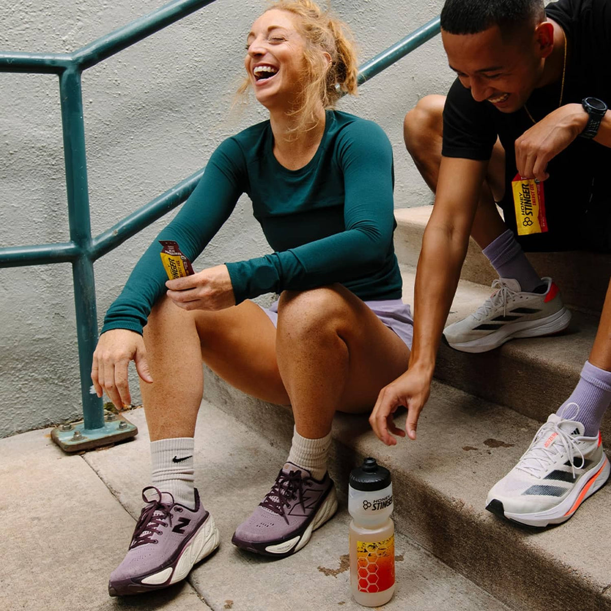 Acai pomegranate energy gel bottle and pouch sitting on steps