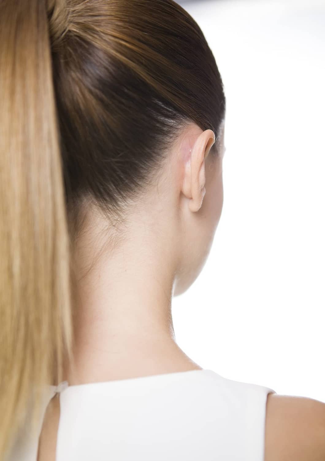 Side profile showing a fitted white ear-correction adhesive pad near the ear