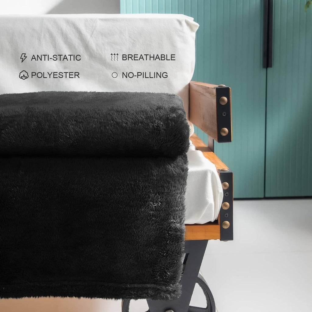 Black plush fleece throw blanket folded on an armchair