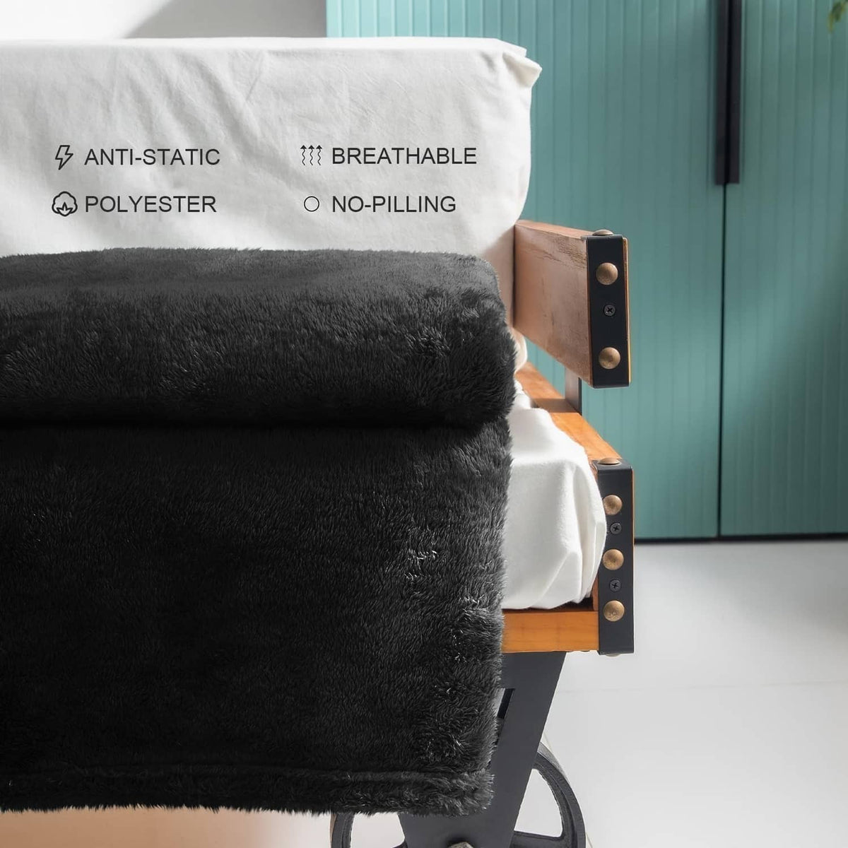 Black plush fleece throw blanket folded on an armchair