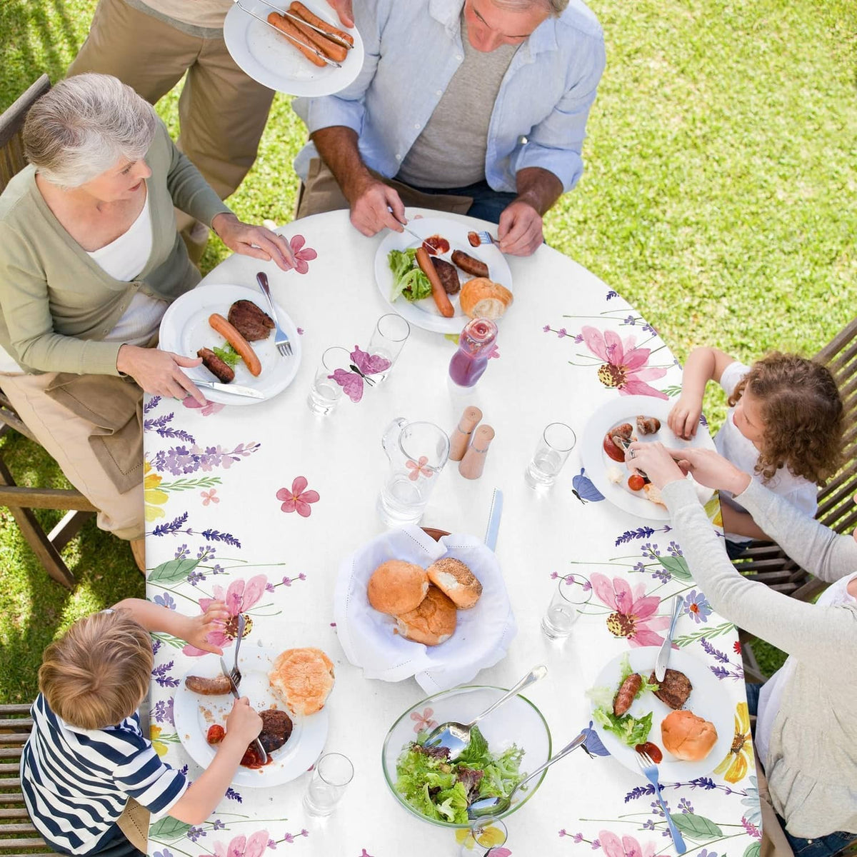 Spring floral tablecloth covering picnic table, white with colorful butterfly and flower print