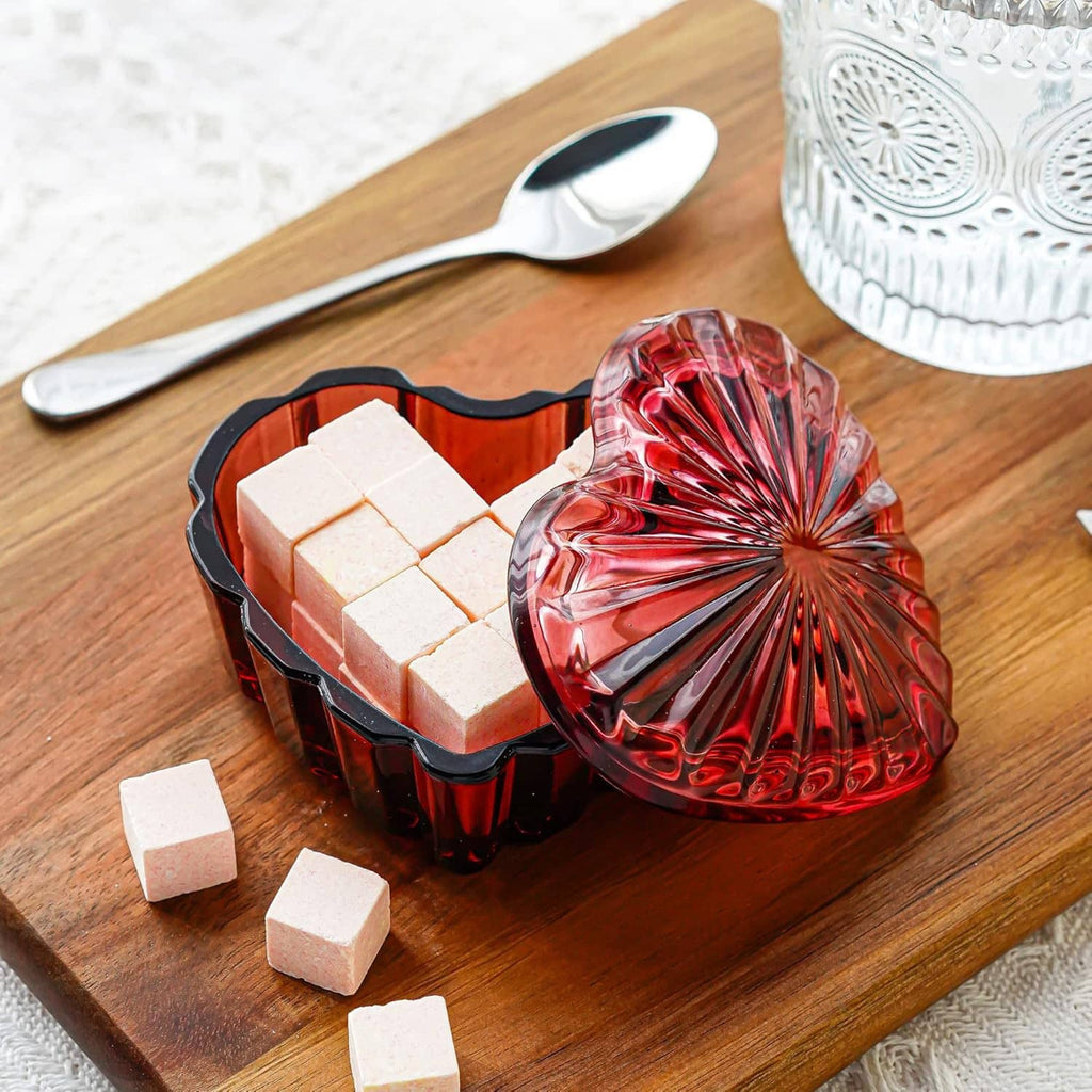Red heart-shaped crystal jewelry box with lid, holding white cubes and ring