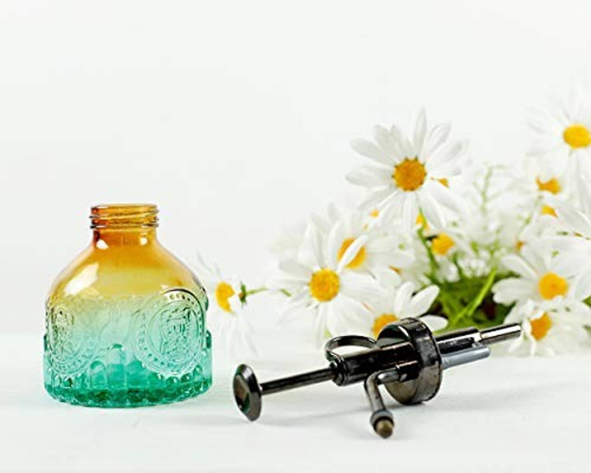 Vintage glass plant mister bottle with amber top, teal base, and black spray handle.