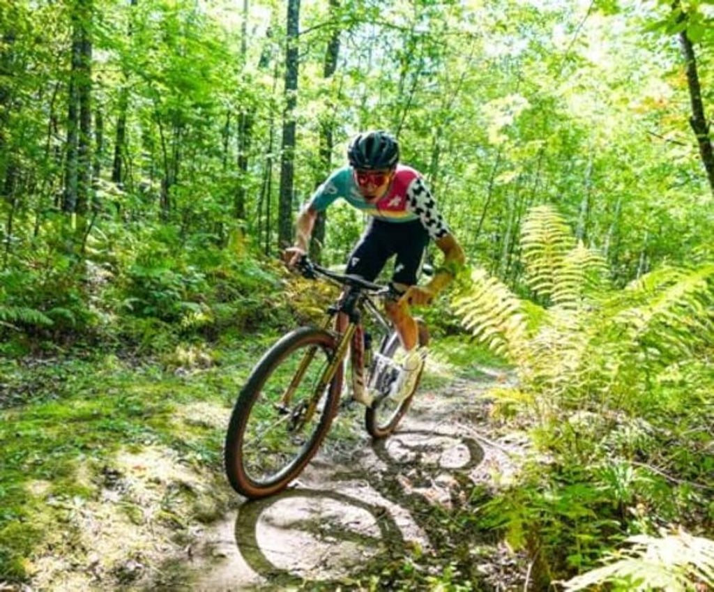 Bike tire sealant featured with a mountain biker riding a trail through greenery