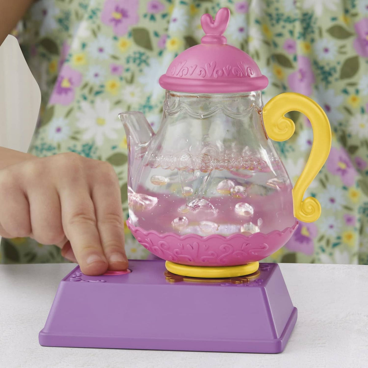 Purple and yellow teapot accessory with clear chamber and pink bubbly liquid on base
