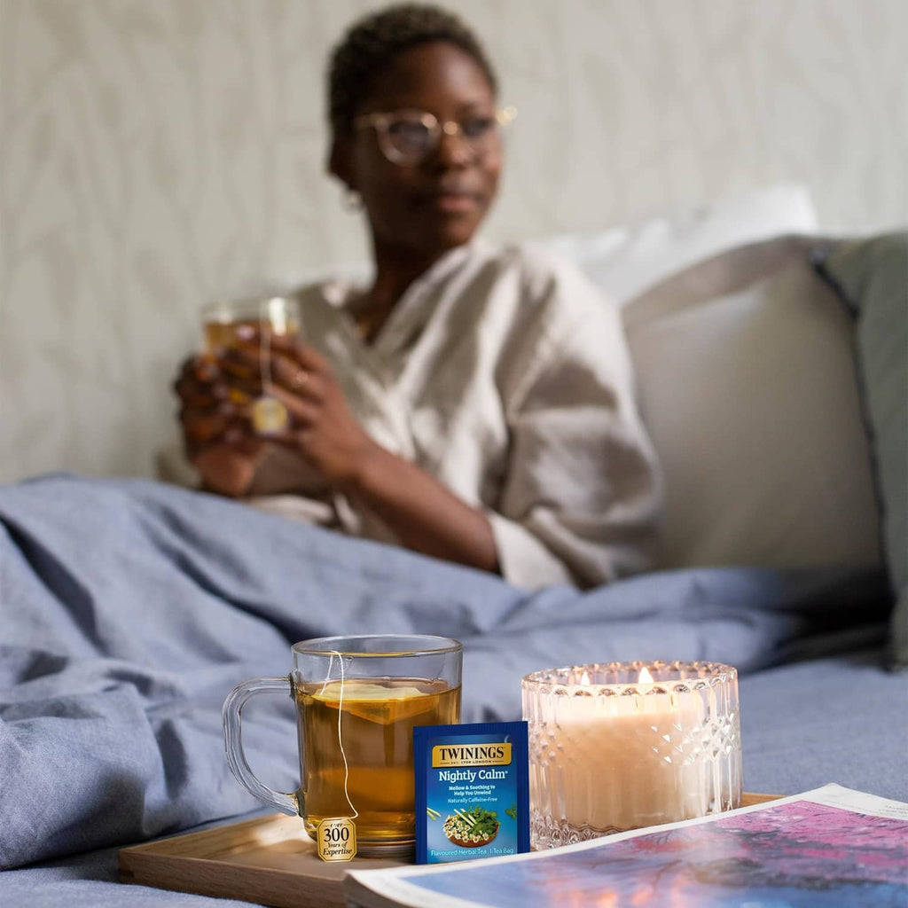 Twinings Nightly Calm herbal tea with glass cups and tea box on bed tray