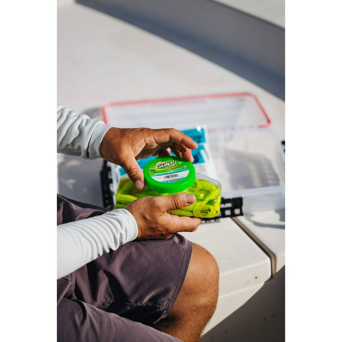 Green fishing bait container held in hands on a boat deck