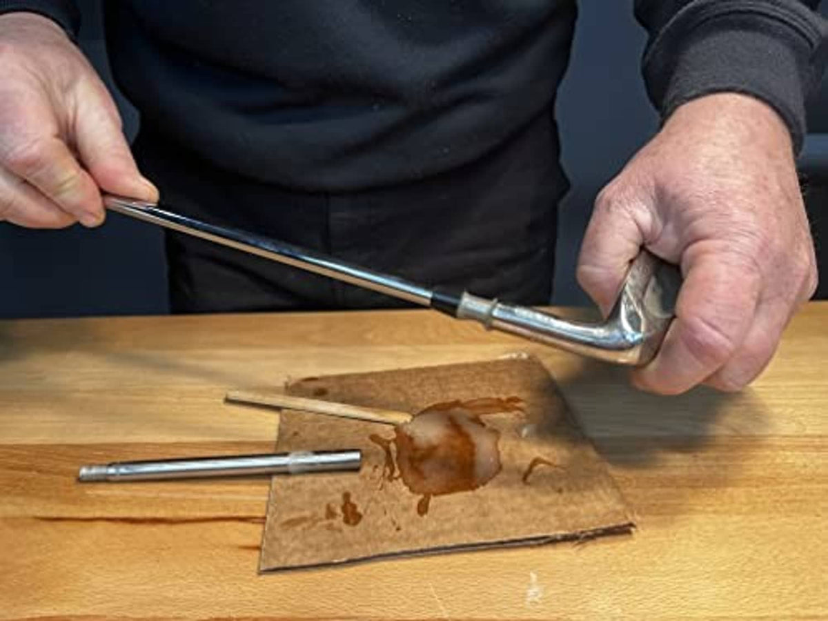 Hands spreading epoxy on a golf club shaft area on a wooden board