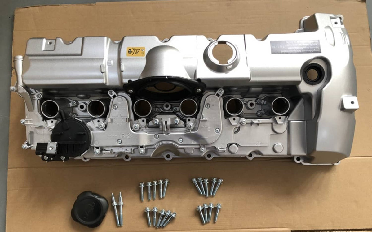 Silver aluminum valve cover with included bolts on cardboard backing