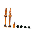 Orange Presta tubeless valve set with two stems, caps, and core removal tool.