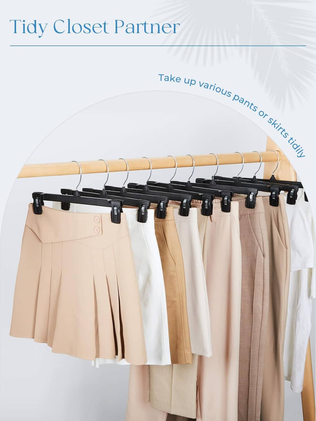 Black clip hangers holding multiple pants and skirts on a wooden closet rod