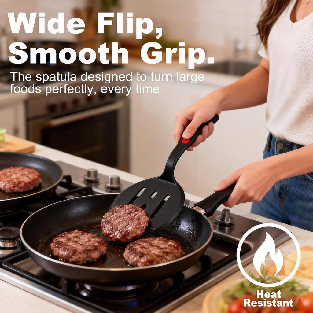 Long black silicone spatula with red grip, slotted head for turning food in a pan