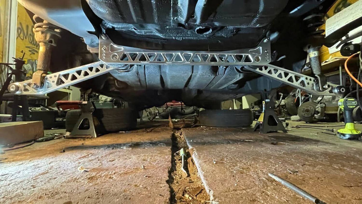 Silver rear subframe brace tie bar undercarriage view with bushings and brackets