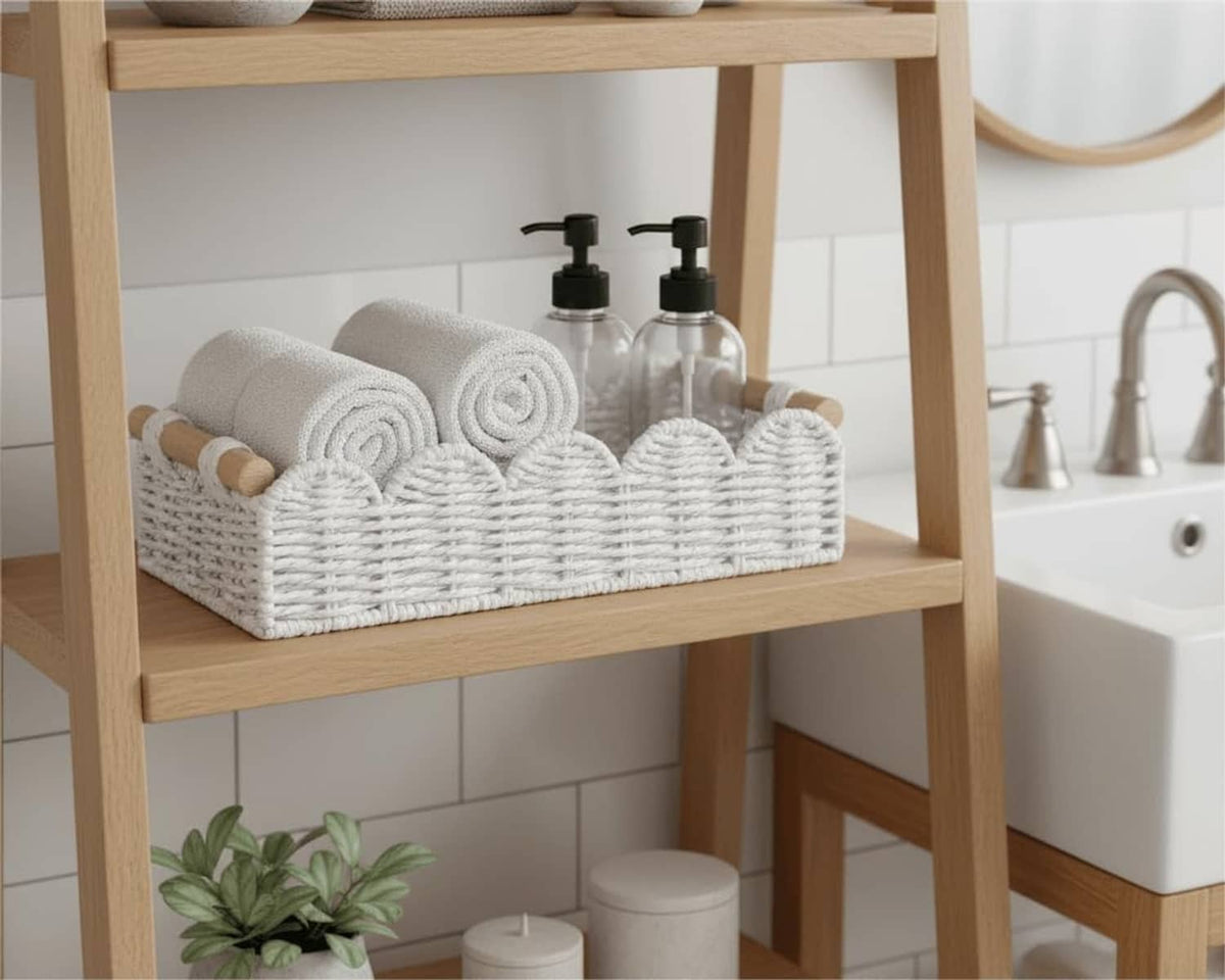 White woven rectangular basket with rope handles on a bathroom shelf, holding folded towels and bottles