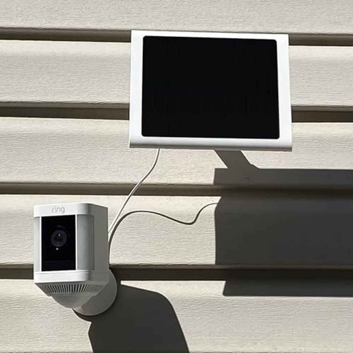 White solar panel charger connected to a Ring-style camera on a wall