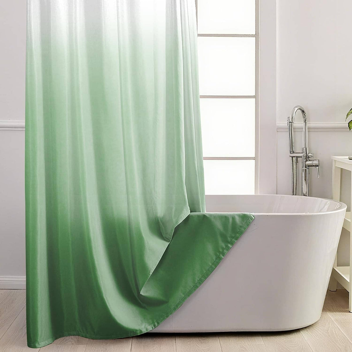 Ombre green shower curtain hanging along a bathtub, with white top and draped pleats