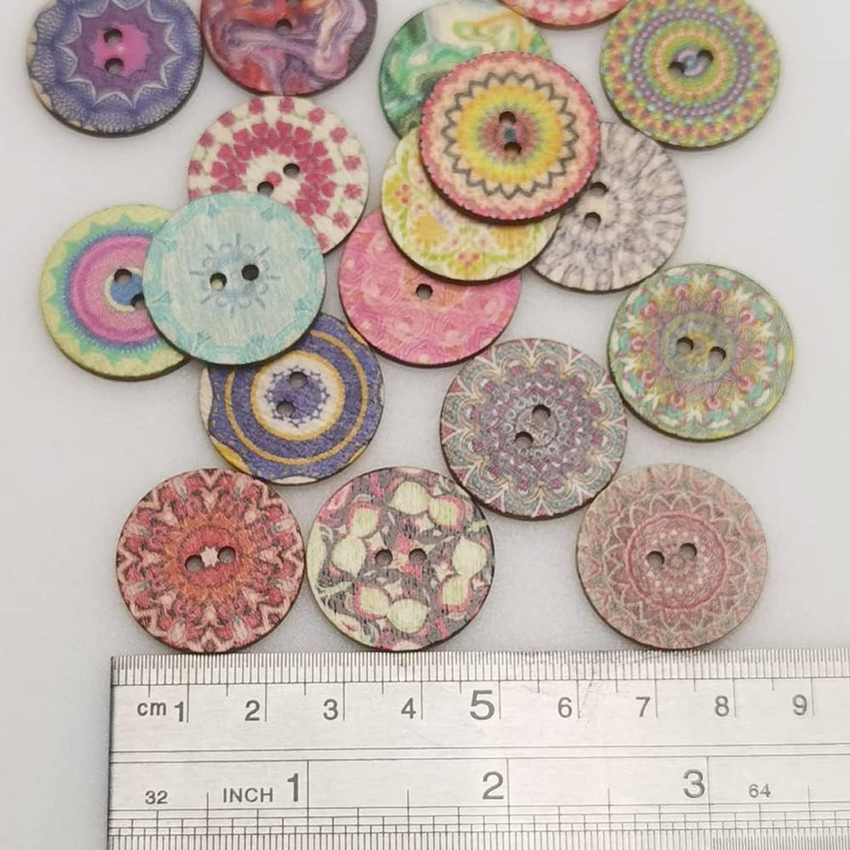 Assorted round wood buttons with colorful prints next to a measuring ruler for size.