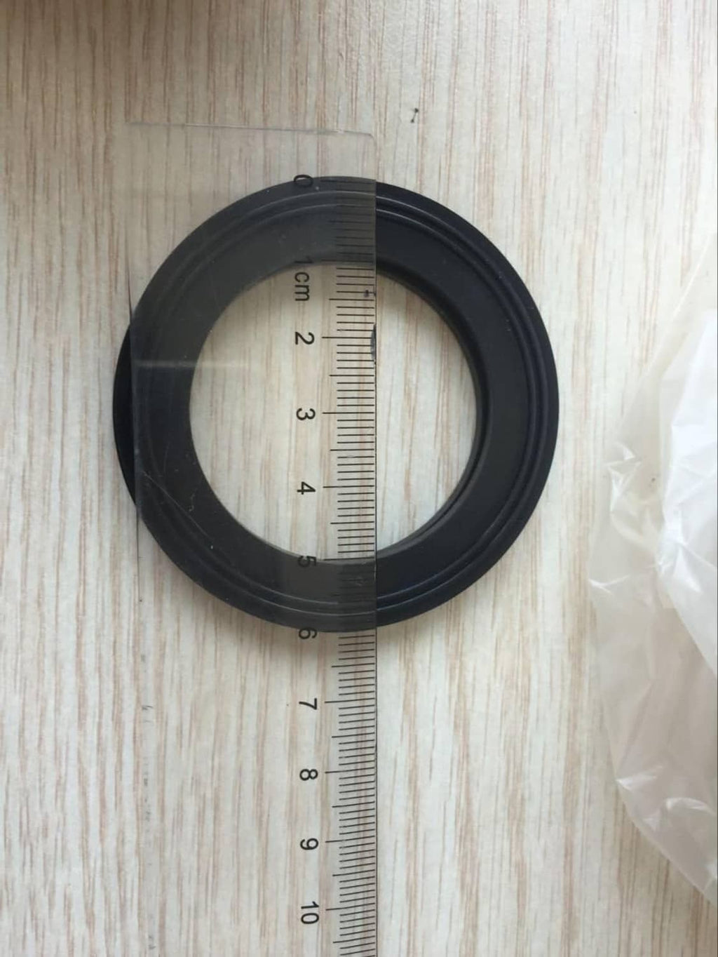 Black threaded bulkhead fitting next to a ruler for size reference