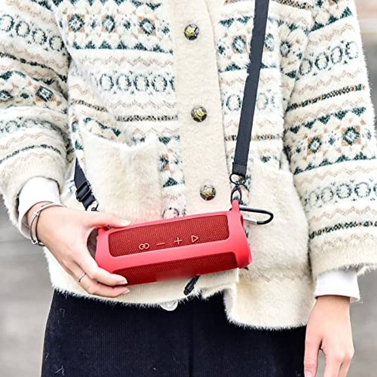 Red silicone speaker case worn crossbody with shoulder strap and metal carabiner clip