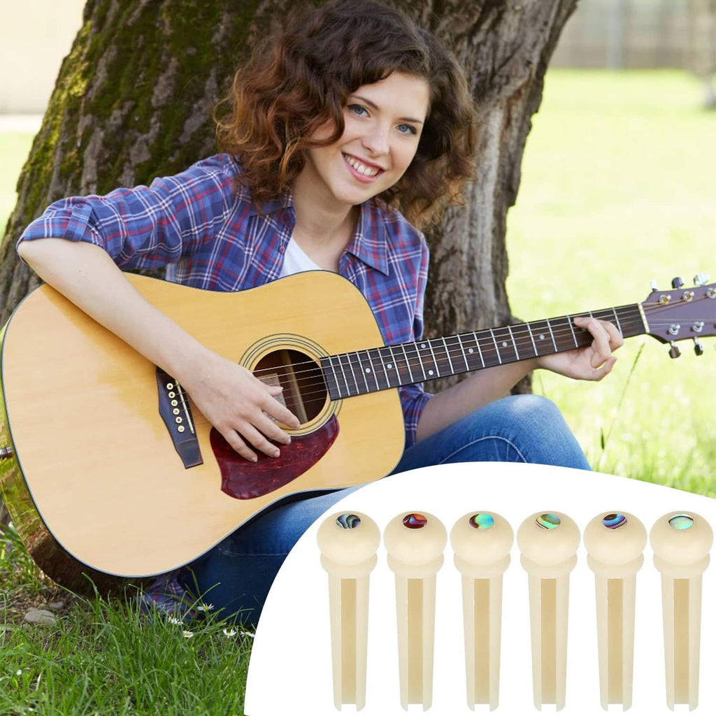 Guitar bridge pins set with iridescent inlay caps shown beside an acoustic guitar