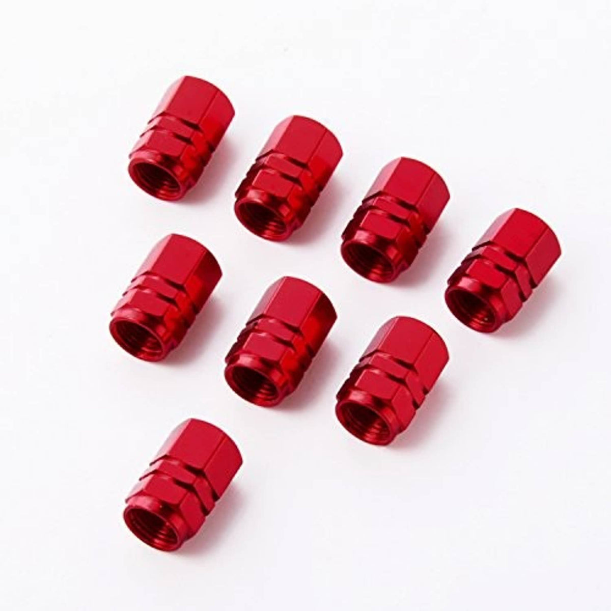 Eight red tire valve stem caps laid out, hex top and ridged metal sides
