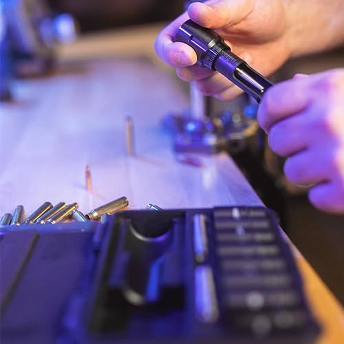 Hands using bullet seating die and micrometer stem during cartridge reloading