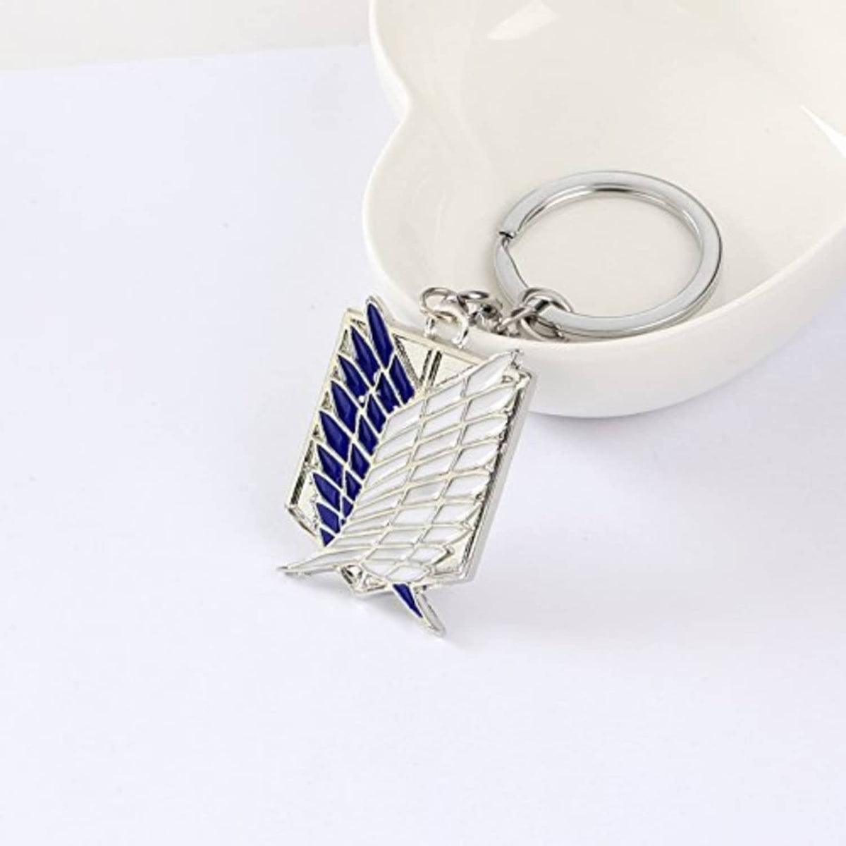 Angled metal keychain with blue-and-silver winged emblem on key ring