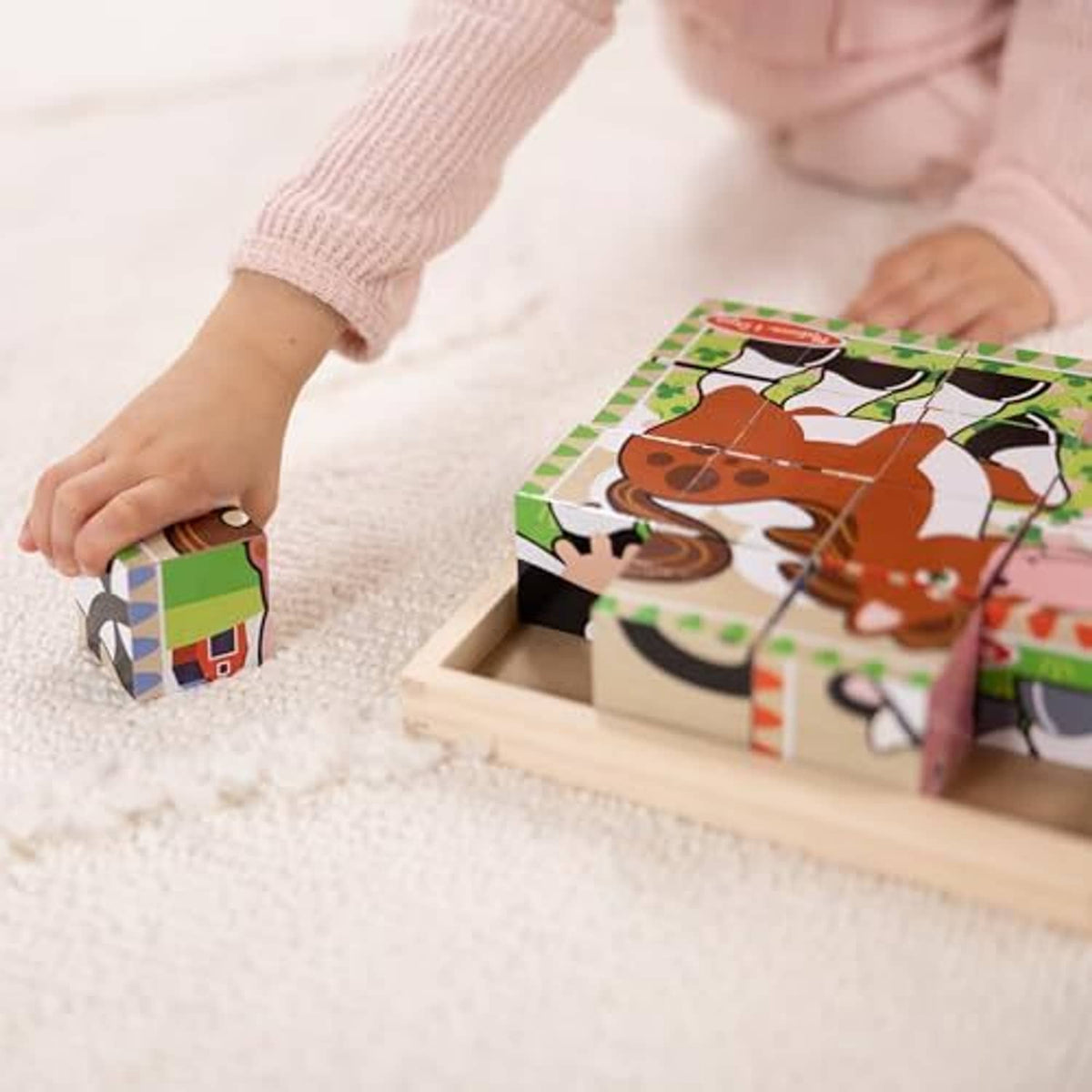 Child playing with wooden farm cube puzzle, stacking colorful animal cubes