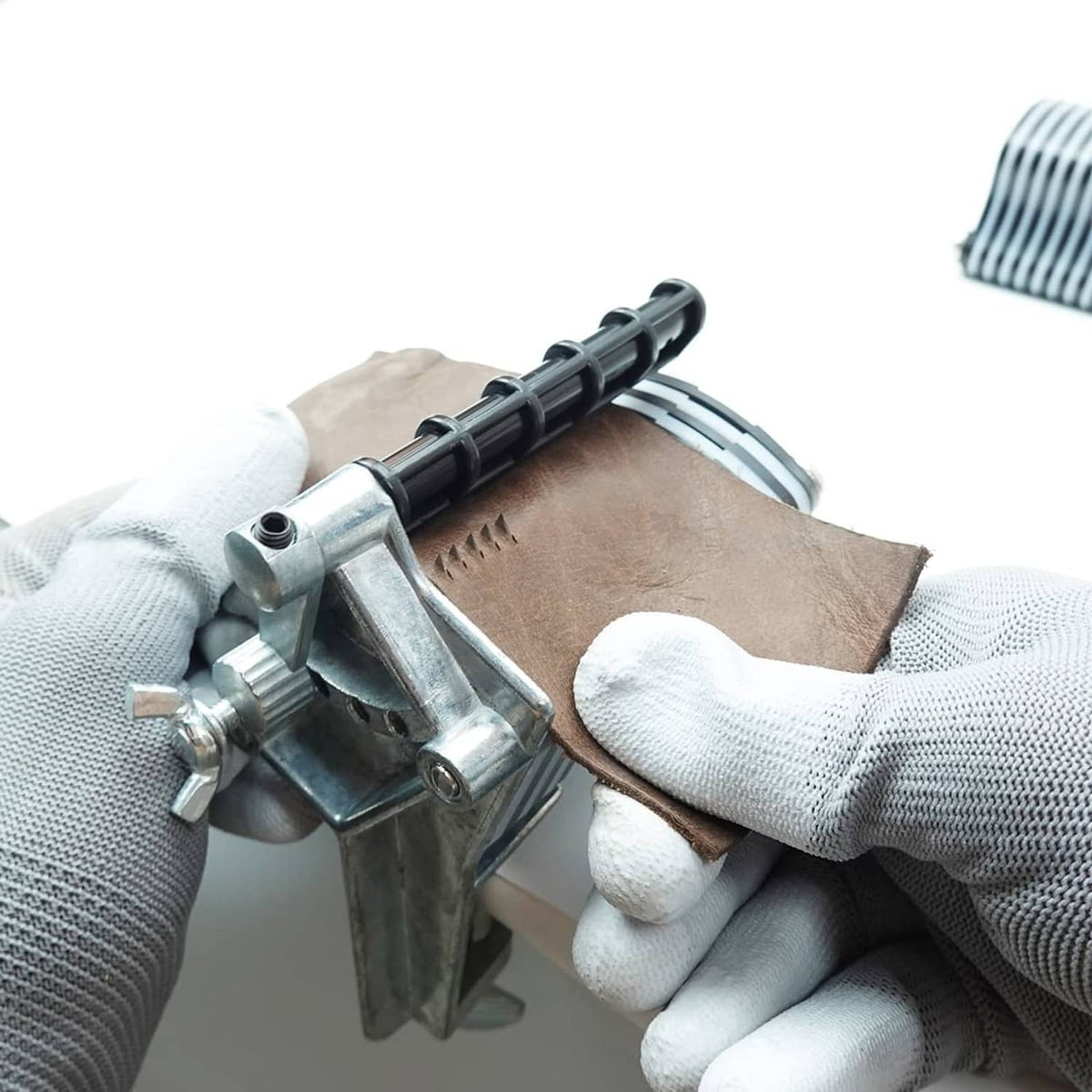 Leather lace cutter in use: blade presses tan leather strip with black roller feed