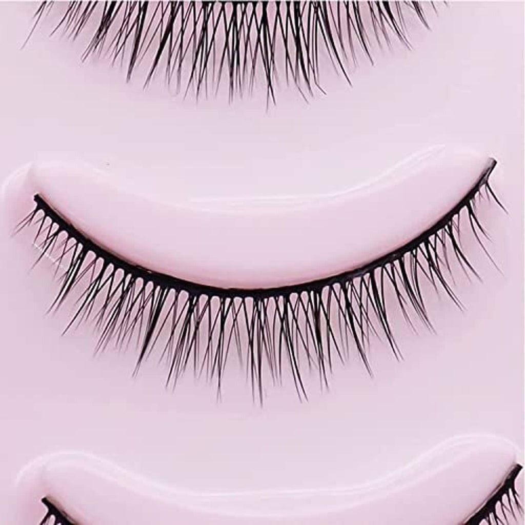 Short black false eyelash strip close-up with curved band and wispy fibers