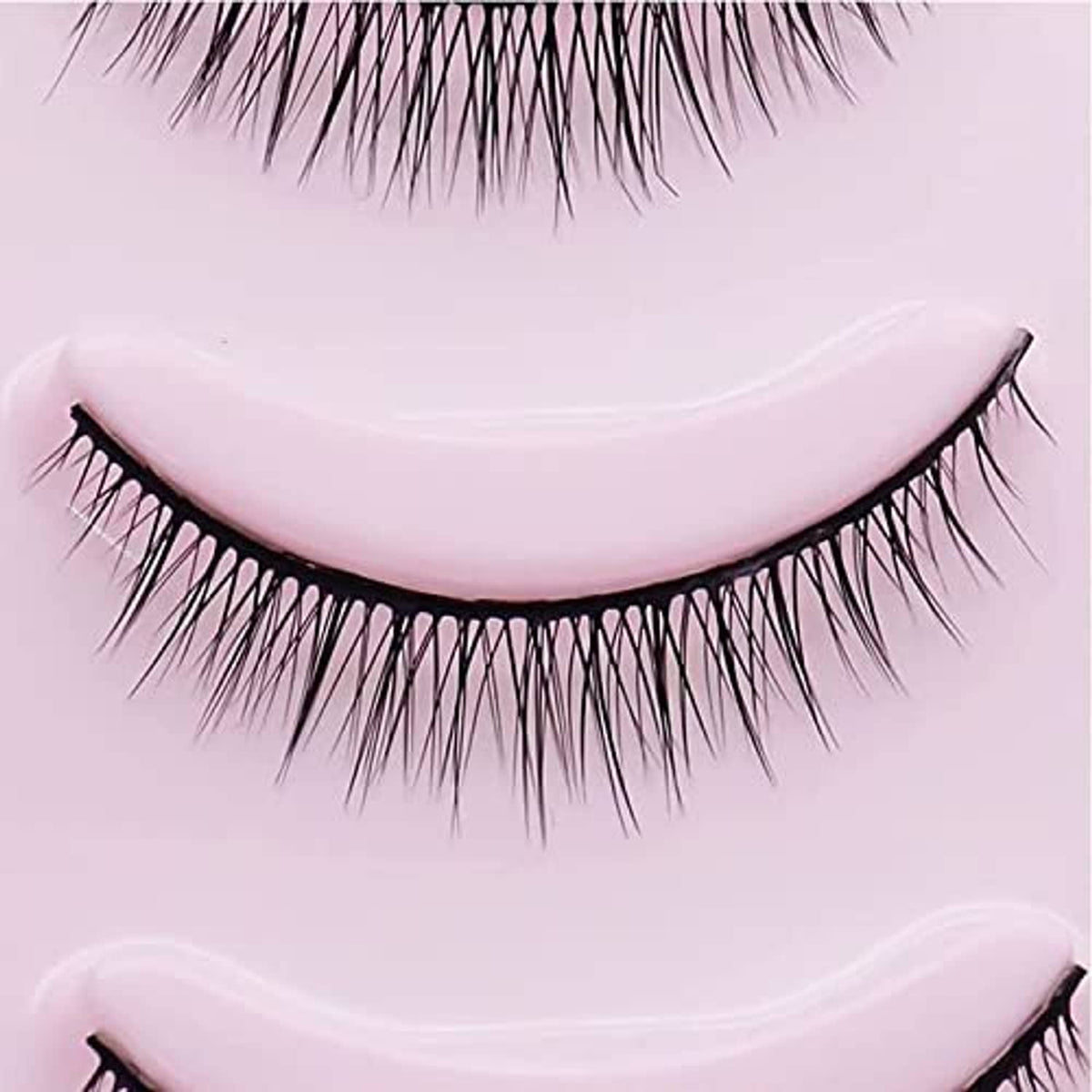 Short black false eyelash strip close-up with curved band and wispy fibers