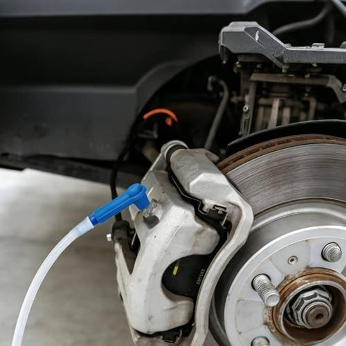 Brake bleeder kit connected to brake caliper with blue check fitting and clear hose
